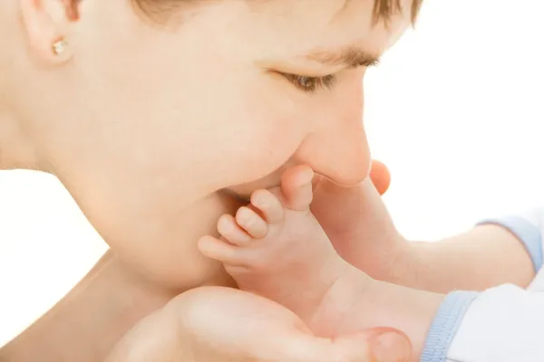 Primer plano de la madre besando los pies del bebé sobre blanco — Foto de Stock