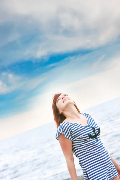 Счастливая девушка в полосатом жилете на фоне моря и неба — стоковое фото
