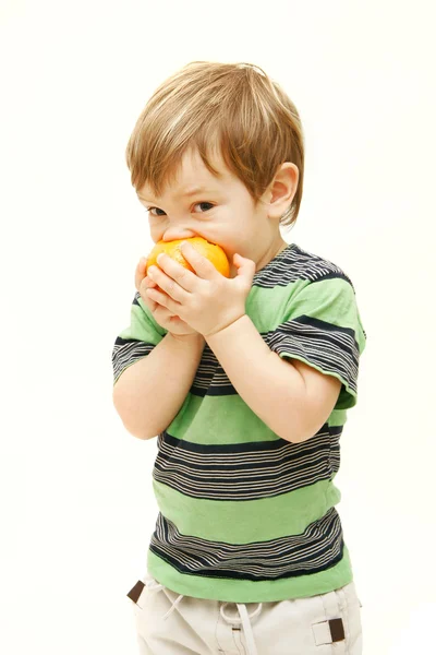 Jovem menino comendo laranja sobre branco — Fotografia de Stock
