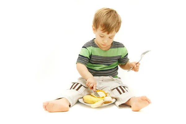 Young boy eating fruits with fork and knife over white — Stock Photo, Image