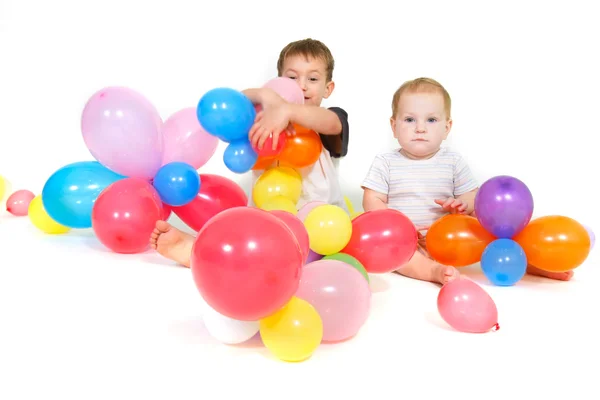 Two children with colorful balloons over white — Stock Photo, Image