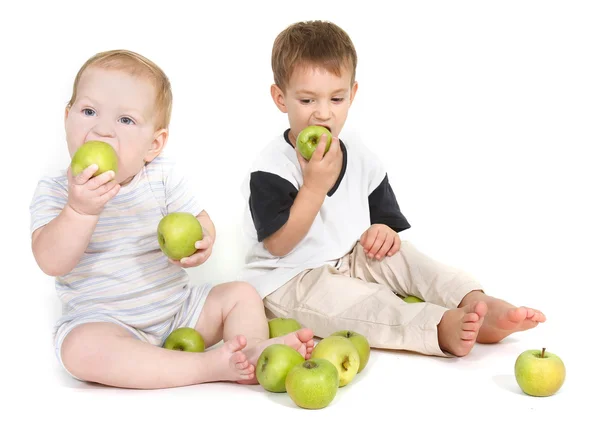 Dvě děti jedí zelená jablka nad bílou — Stock fotografie