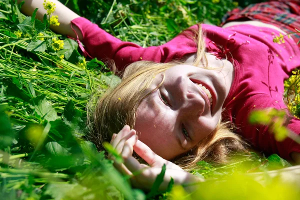 Menina feliz que coloca na grama verde — Fotografia de Stock