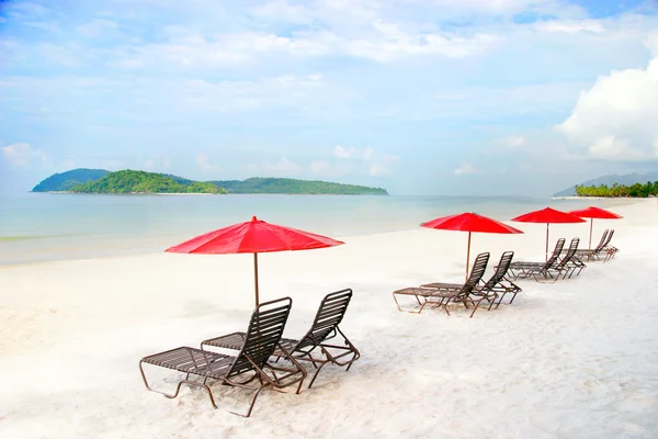 Sedili e ombrelloni sulla spiaggia di sabbia ai tropici — Foto Stock