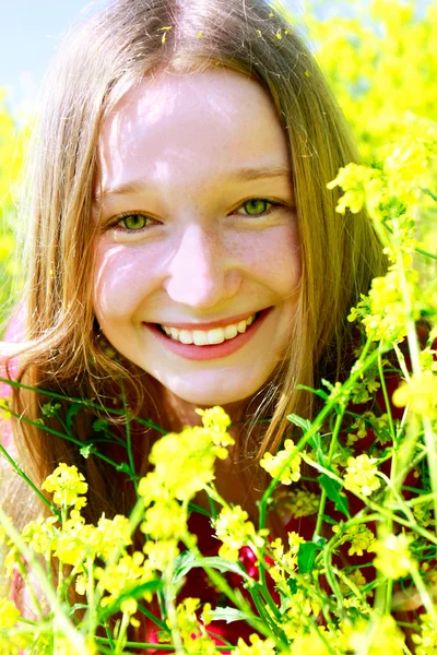 Happy girl in yellow flowers outdoors — Stock Photo, Image