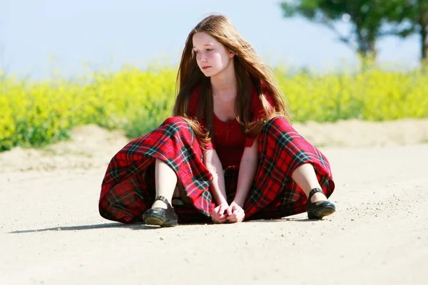 Menina triste com cabelos longos sentado na estrada do campo — Fotografia de Stock