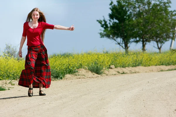 幸せな女の子の国の道路上でヒッチハイク — ストック写真
