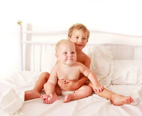 Двое детей сидят в кровати — стоковое фото