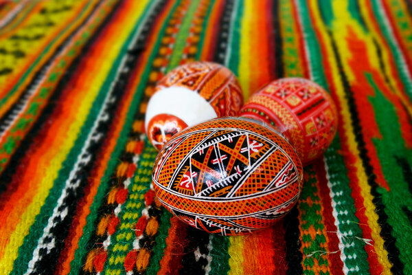 three hand-made eater eggs on traditional textile background