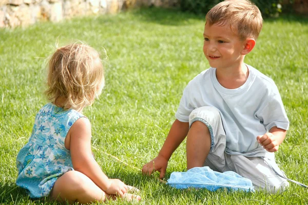 Двое детей играют на зеленой траве — стоковое фото