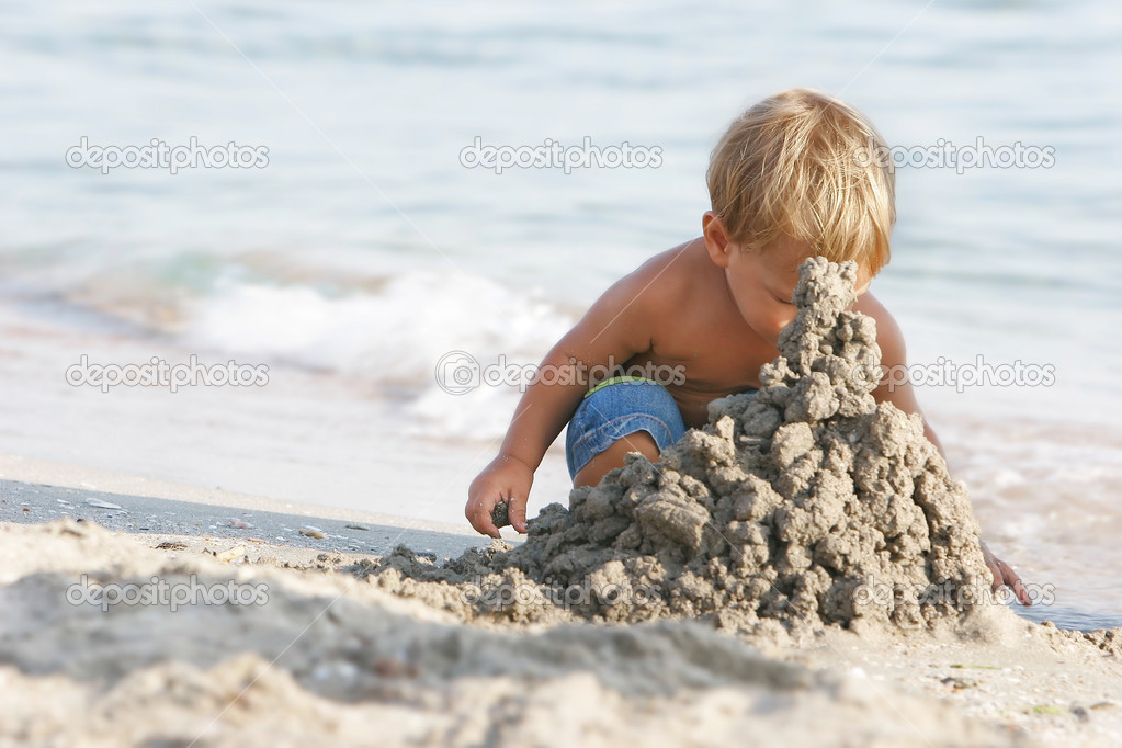 baby boy playing with sand on beach