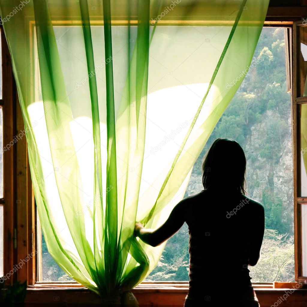 female silhouette at open window in old hotel