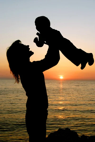 Mutter spielt mit ihrem Sohn im Hintergrund des Sonnenuntergangs — Stockfoto