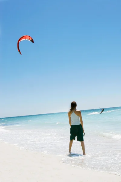 Girl looking at kite surfer in the sea — Stock Photo, Image