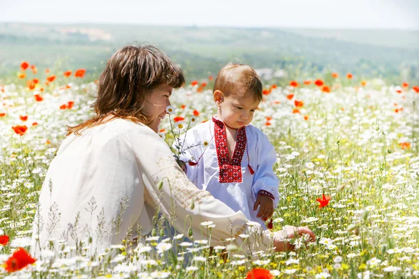 Mother and son in traditional clothes in flower field — Stock Photo, Image