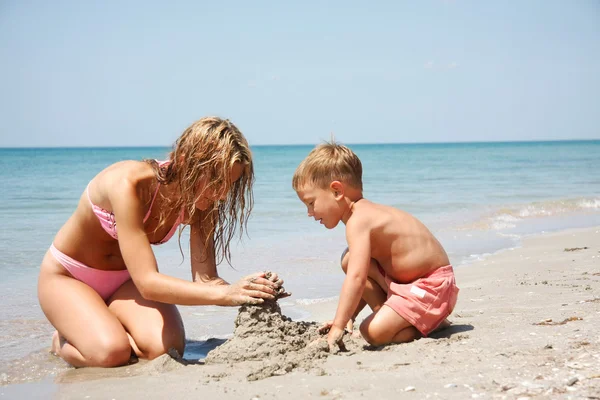 Mother and son building sand castle on beach — Zdjęcie stockowe