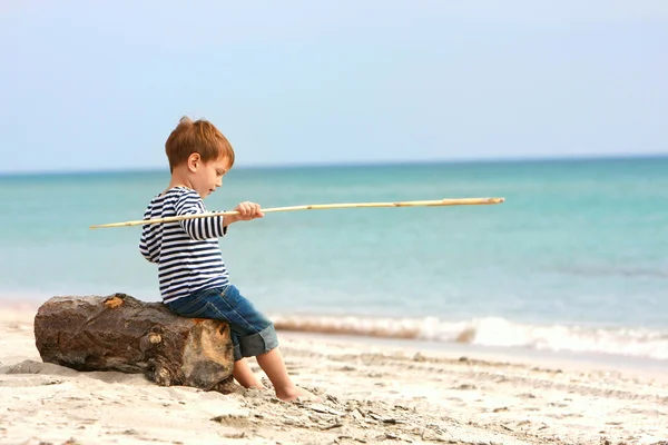 Schattige jongen zittend op zand strand — Stockfoto