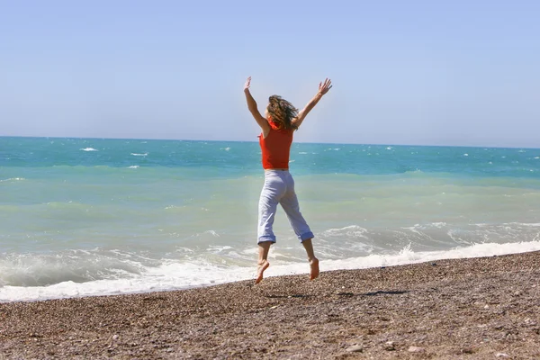 Jonge vrouw gelukkig springen op het strand — Stockfoto