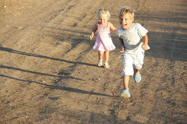 Duas crianças a correr por estrada rural — Fotografia de Stock