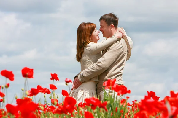 Joven pareja amorosa en rojo amapolas campo — Foto de Stock