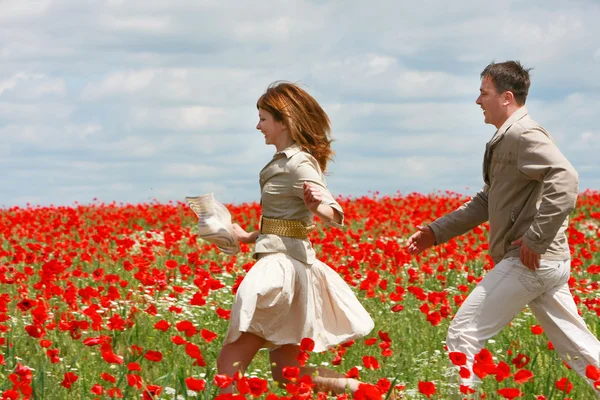 Happy couple in red poppies field — Stock Photo, Image