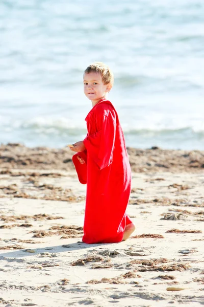 Cute young boy in big t-shirt walking on sand beach — Stock Photo, Image