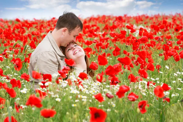Jovem casal amoroso no campo de papoilas vermelhas — Fotografia de Stock
