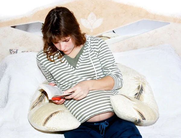 Mujer preganant libro de lectura en la cama —  Fotos de Stock