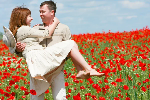 Happy couple in red poppies field — Stock Photo, Image