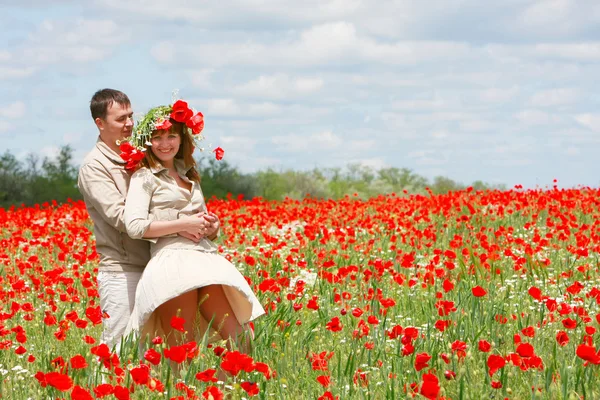 Casal feliz no campo de papoilas vermelhas — Fotografia de Stock