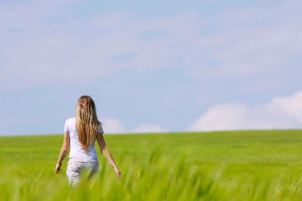 young girl going away in green field