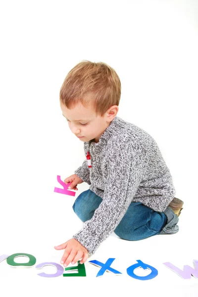 Jovem menino brincando com letras sobre branco — Fotografia de Stock