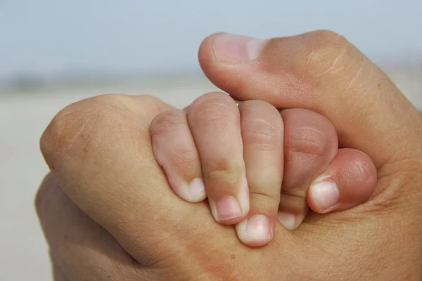 Babyhand i vuxen hand — Stockfoto