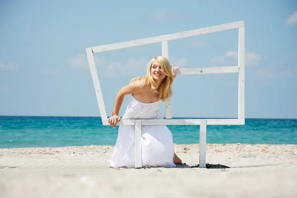 Young happy girl looking through wooden window on sea background — Stock Photo, Image