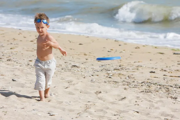 Junge Biy spielt Frisbee am Strand — Stockfoto