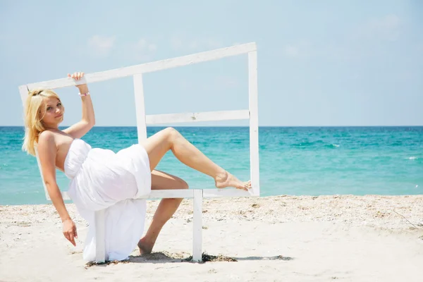 Gelukkig meisje, zittend op houten venster op strand — Stockfoto