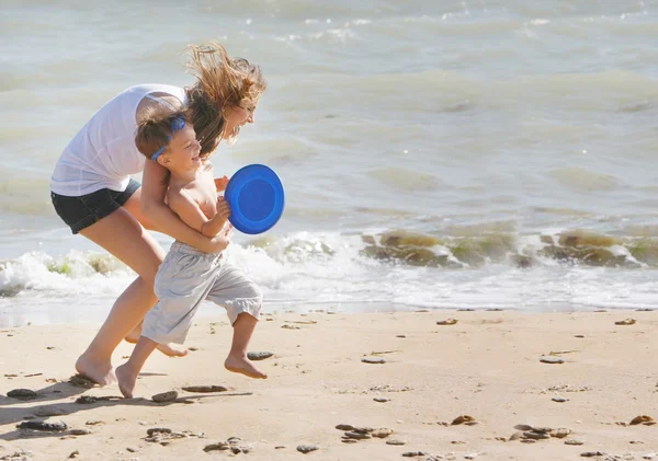 Mãe e filho jogando frisbee na praia — Fotografia de Stock