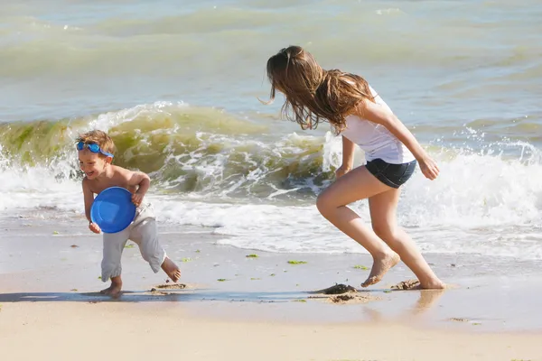 Moeder en zoon frisbee spelen op strand — Stockfoto