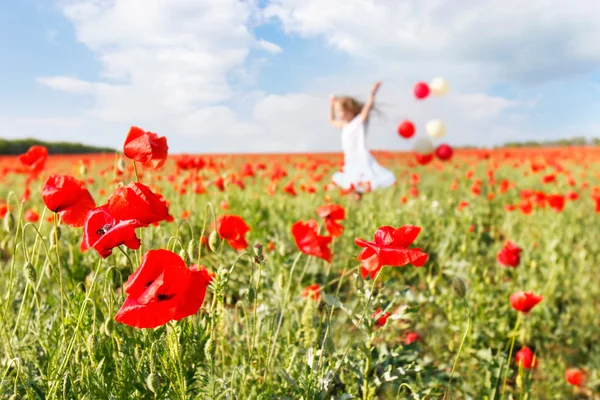 Happy girl with colorful balloons running in poppy field — Stock Photo, Image