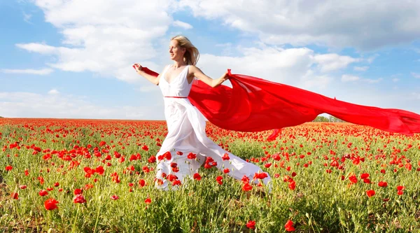 Mujer feliz corriendo con bufanda roja en el campo de amapola —  Fotos de Stock
