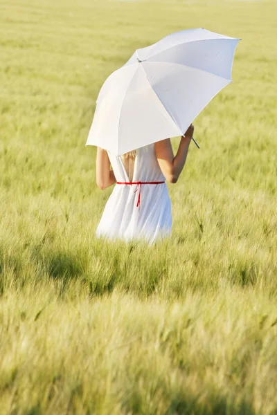 Frau in weißem Kleid mit Regenschirm verschwindet im Grünen — Stockfoto