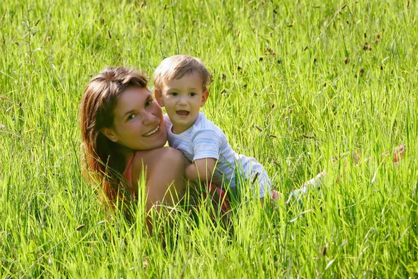 Gelukkig moeder en zoon spelen in gras — Stockfoto