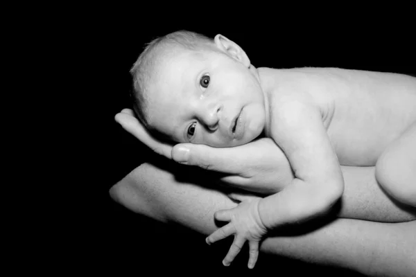 Bebê em mãos do pai sobre preto — Fotografia de Stock