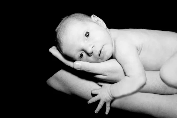 Dítě v otcových rukou nad černou — Stock fotografie