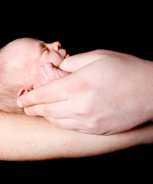 Baby i faderns händer över svart — Stockfoto