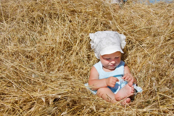 Cute toddler girl playing in haystack — Stock Photo, Image