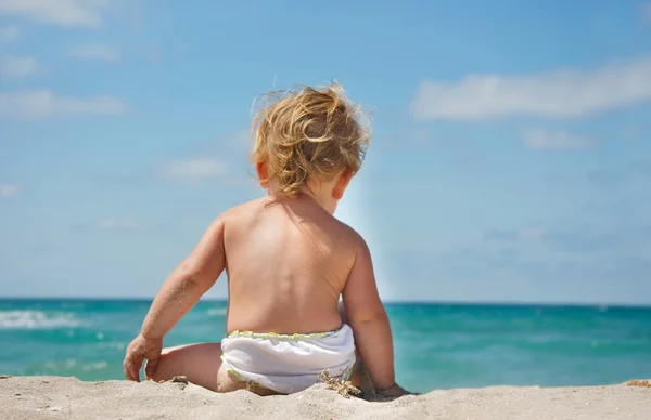 Dziecko, siedząc na plaży i patrząc na morze — Zdjęcie stockowe