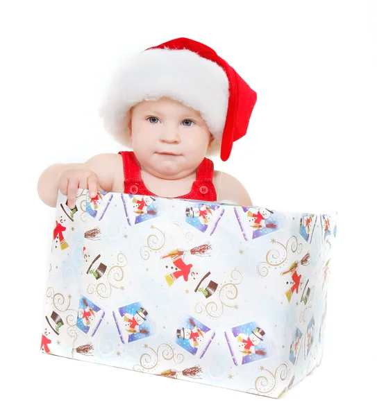 Criança bonito em santa chapéu sentado na caixa de presente sobre branco — Fotografia de Stock