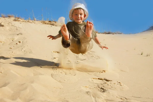 Jonge jongen springen in zand — Stockfoto
