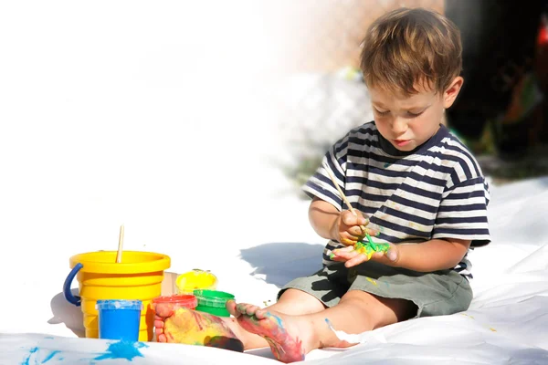Young boy painting outdoors partly isolated over white — Stockfoto